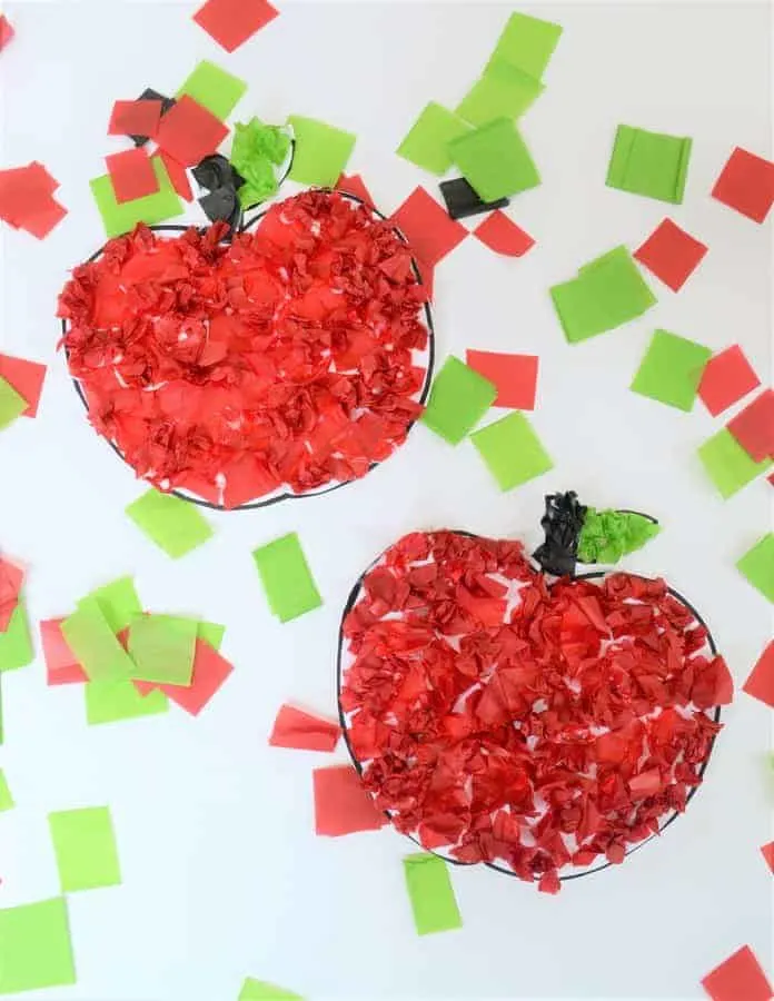 A piece of paper has two apples on it that are created from little squares of red and green tissue paper that have been glued onto the apple outlines.