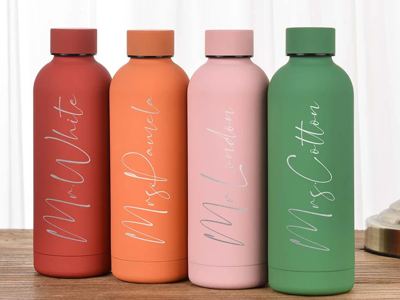 4 water bottles in red, orange, pink, and green are shown with names engraved on them (personalized teacher gifts)