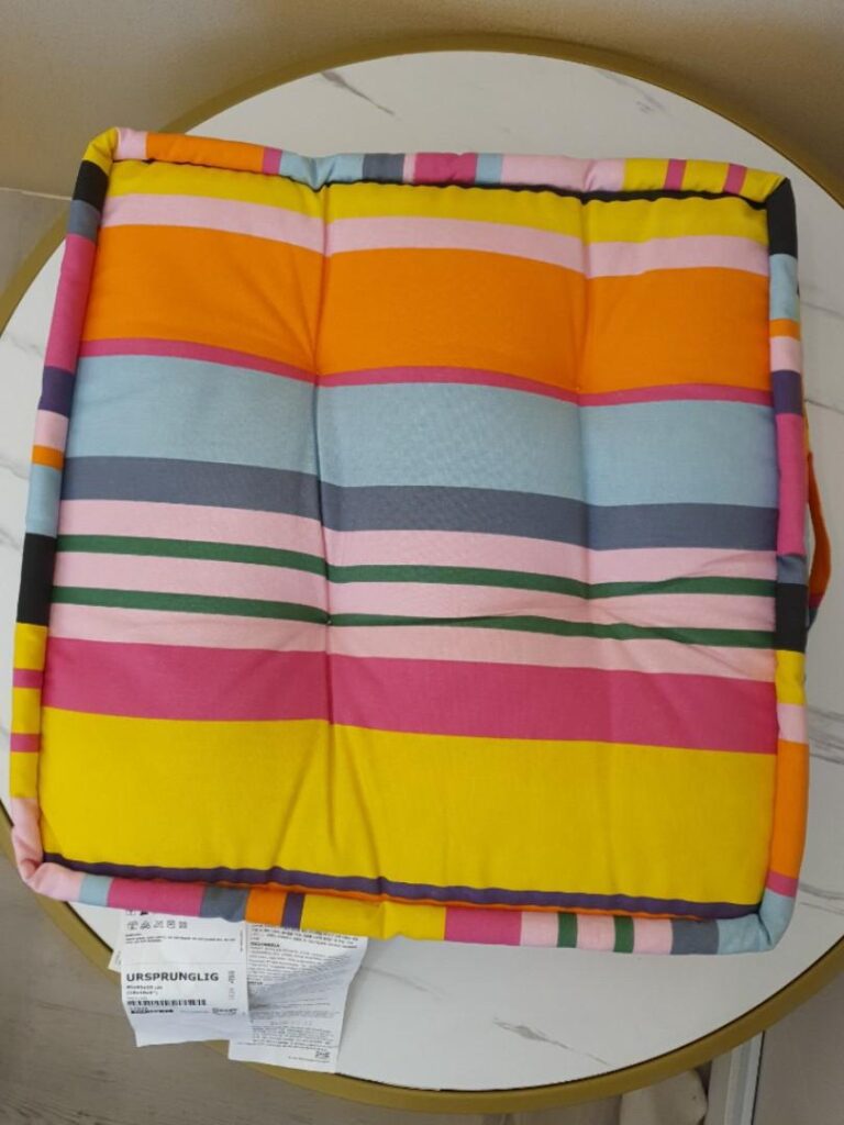 A large, multi colored, striped floor cushion is pictured.