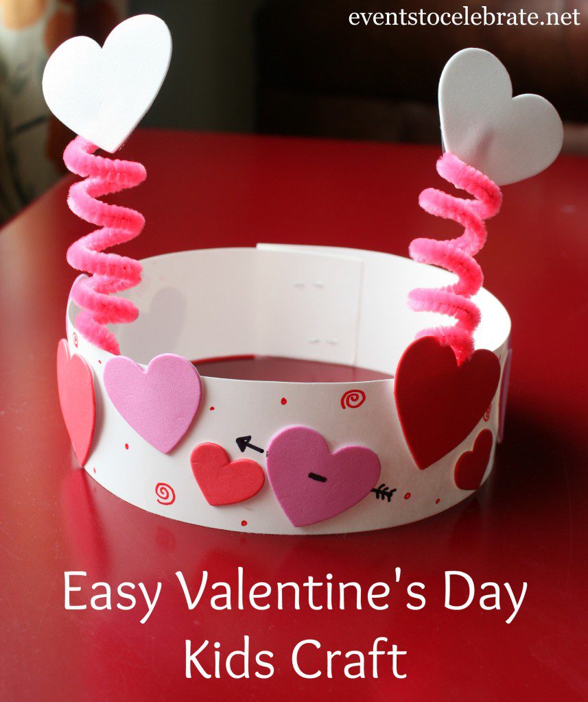 A piece of paper is shaped into a headband with heart stickers all over it. Pipe cleaners are made to look like antennas.