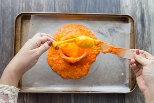 Student playing with orange bubbling slime over a cookie sheet