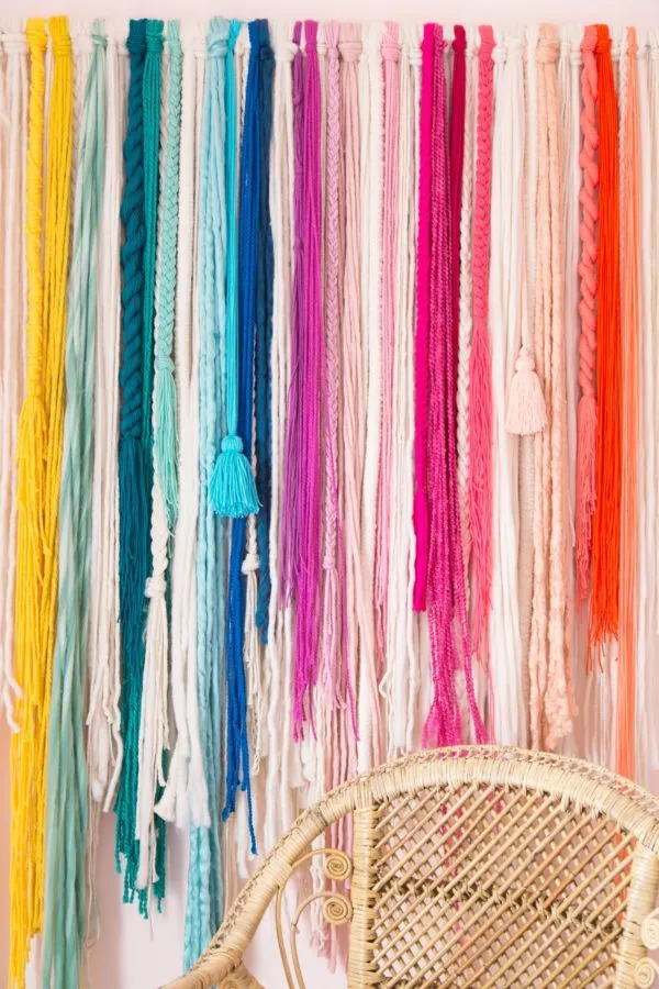 a wall hanging consisting of strands of different colored and textured yarn