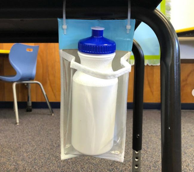 A shoe holder pocket trimmed and attached to a student desk with zip ties to hold a water bottle