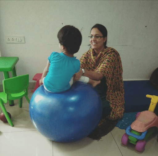 Child playing on blue yoga ball with adult